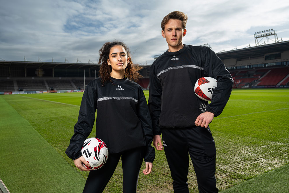 Two players wearing O'Neills windbreaker jackets during outdoor training in lightweight performance outerwear.